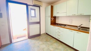 Une cuisine avec des meubles de couleur vert clair, un plan de travail en bois et une cuisinière intégrée.