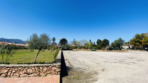 Un vaste espace extérieur agrémenté d’un mur en pierre, d’une pelouse verdoyante et d’un ciel d’un bleu éclatant.