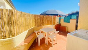 Une terrasse avec une table et des chaises, une clôture en bois et un sol carrelé.