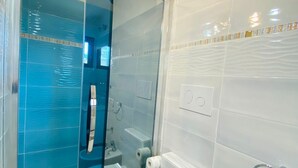 Une salle de bain avec une paroi en verre, des toilettes, un lavabo et une baignoire.