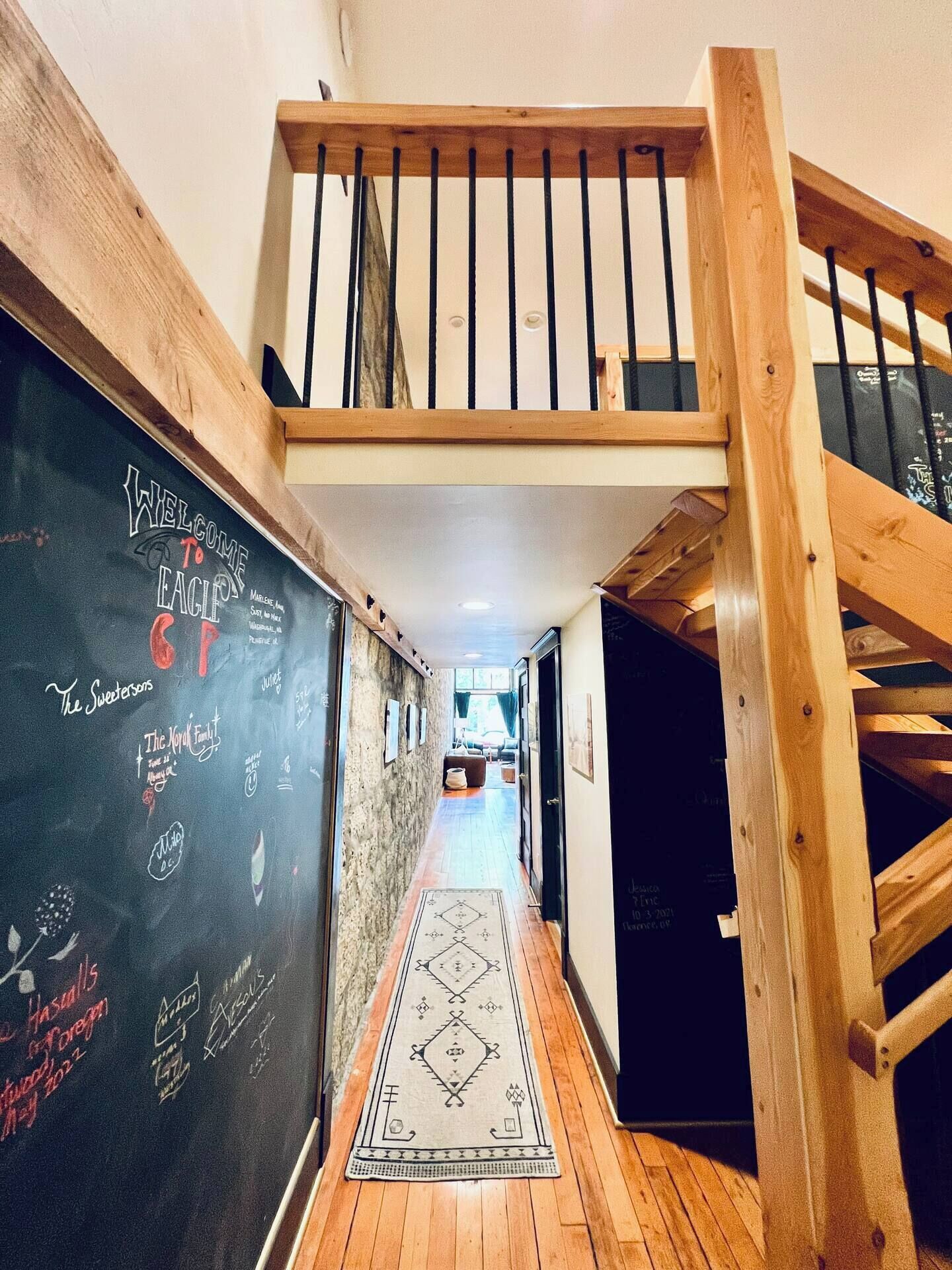 Eine Holztreppe führt zu einer Landebene im zweiten Stock. An der linken Wand befindet sich eine Tafel mit verschiedenen Schriftzügen und Zeichnungen.