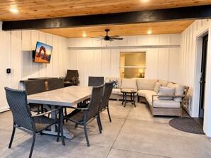 A dining area with a table and chairs, a sofa, and a ceiling fan.