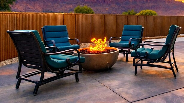 An outdoor seating area with four chairs and a fire pit, surrounded by a wooden fence and a view of a mountain range. - Moab Desert Escape Villa: Luxury 5-Bedroom Retreat with Heated Pool (Moab)
