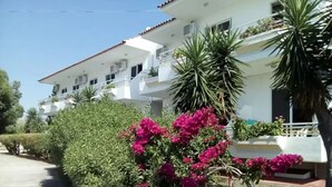 Un bâtiment blanc doté de balcons, entouré de verdure et de fleurs de bougainvillier.