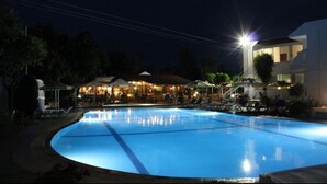Une piscine la nuit, avec un bâtiment en arrière-plan.