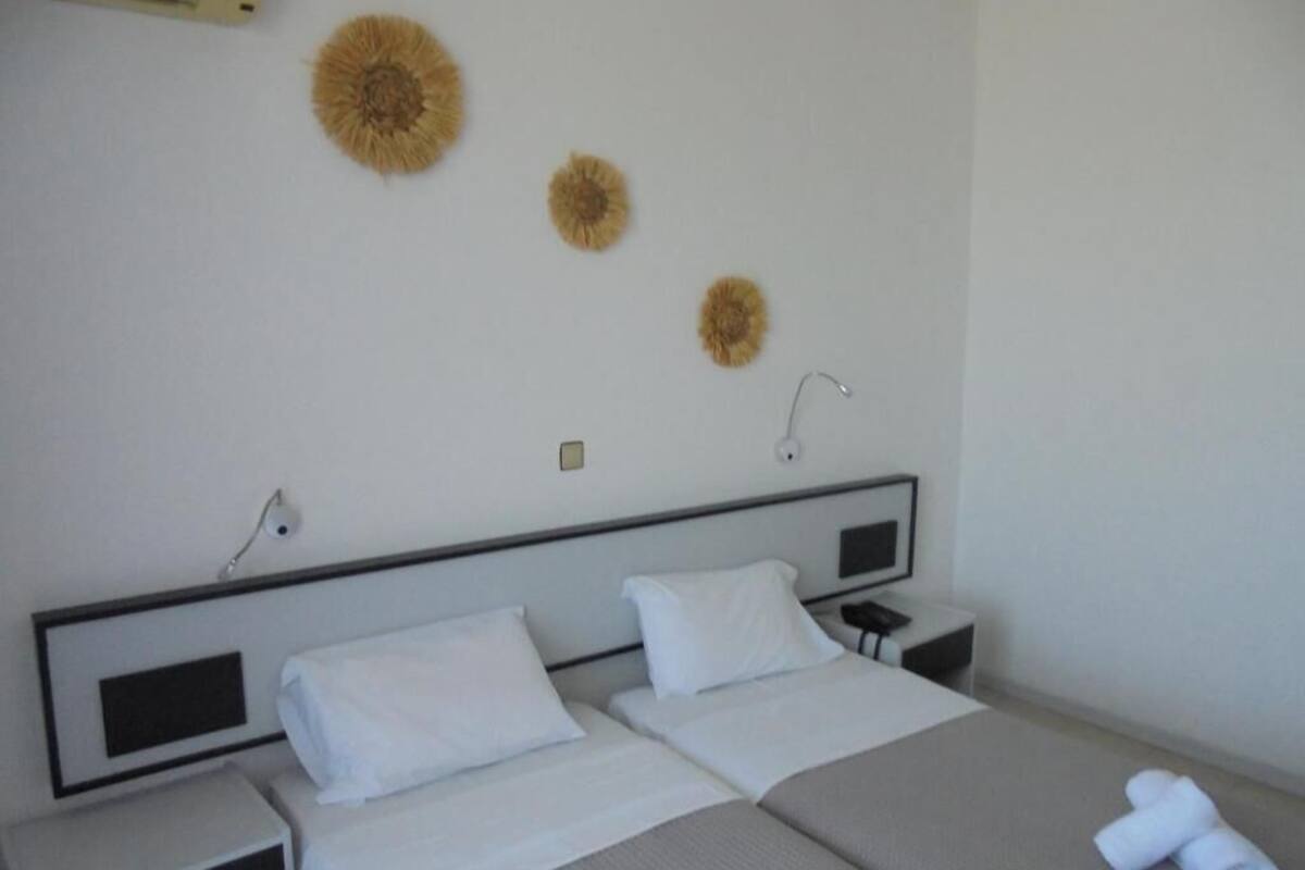 Une chambre d’hôtel avec deux lits, une table de chevet, une lampe et des œuvres d’art décoratives au mur.