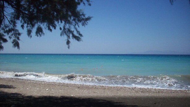 Une plage à l’eau turquoise et limpide, bordée d’un rivage sablonneux.