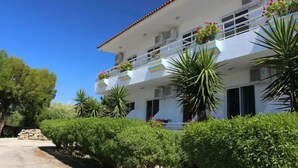 Un immeuble à plusieurs étages doté de balcons, entouré de verdure et surplombant un ciel dégagé.
