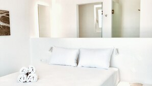 A modern hotel room with a large bed, a bedside table, and a mirror. - Queen Double Room by Bianco a Nero Mykonos (Πλιντρί)