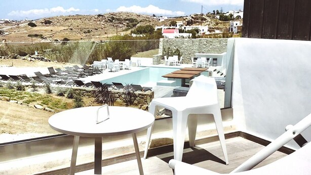 A terrace with a pool, white lounge chairs, and a table. - Queen Double Room by Bianco a Nero Mykonos (Πλιντρί)