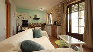 Un accogliente soggiorno con divano e tavolo da pranzo, una cucina con forno a microonde e lavastoviglie, e un'ampia finestra con tende.
