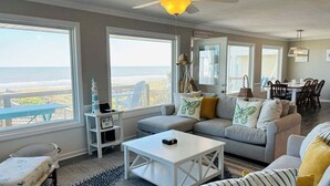 Un salon avec vue sur l’océan, un ventilateur de plafond, un coin repas et un panneau indiquant la présence d’une connexion Wi-Fi.