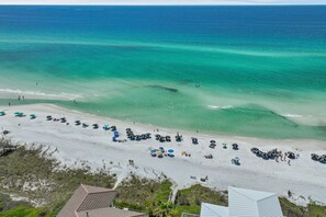 An aerial view of a beach with tents and umbrellas, a sandy shore, and the ocean. - Private Beach, Pickleball, Tennis 3 heated pools! (Santa Rosa Beach)