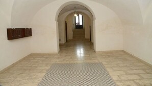 Un couloir avec un tapis à motifs, un panneau de bois sur le mur et un escalier menant à une autre pièce.