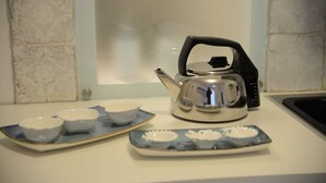 Un plan de travail de cuisine avec une bouilloire, deux bols et une assiette ornée d’un motif bleu.