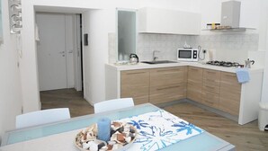 Une cuisine moderne avec des meubles blancs, un four à micro-ondes et une cuisinière à gaz.