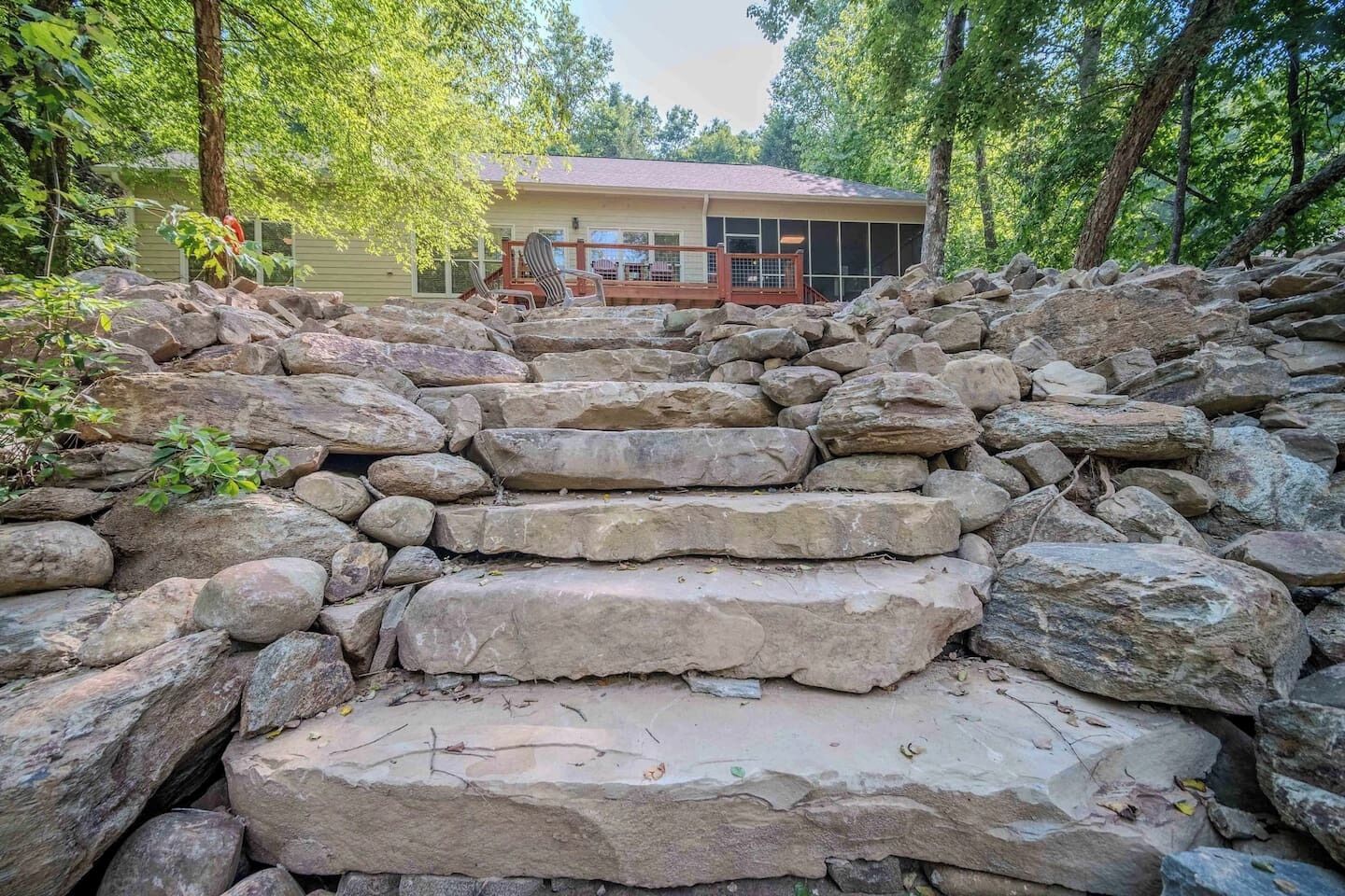 Un escalier en pierre menant à une maison entourée d’arbres.