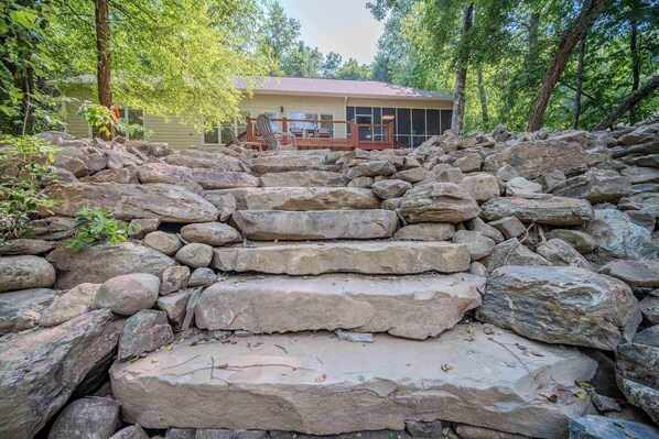 A stone staircase leading to a house surrounded by trees.
