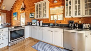 A kitchen with white cabinets, stainless steel appliances, and wooden ceiling beams. - Shore Enough - Duck, Sanderling, 50 Yds to Beach, Elevator, Pets OK, Community Pool, Flex Stays (Duck)