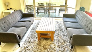 Una sala de estar con dos sofás grises, una mesa de centro de madera y una alfombra mullida.