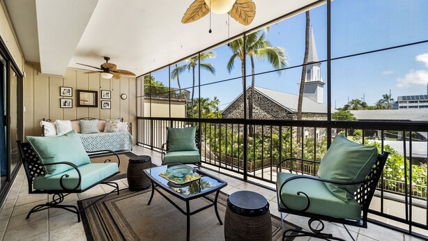 A balcony with a ceiling fan, a sofa, and chairs with cushions.