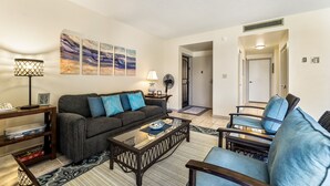 A living room with a sofa, armchairs, a coffee table, and artwork on the wall.