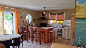 A compact kitchen with a dining area, featuring a central island, wooden chairs, and a small table. - Entire house 10 metres from the beach (Lège-Cap-Ferret)