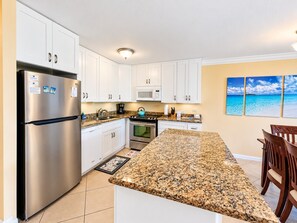 A modern kitchen with white cabinets, stainless steel appliances, and a granite countertop. - Kamaole Sands #9-111 Family-Friendly Suite Near Famous Kamaole III Beach (Kihei)