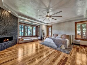 A spacious bedroom with a large bed, a fireplace, and a ceiling fan. - Lake View 545 Lodgepole | 6BR/6.5BA Incline | Hot Tub, Game Room (Incline Village)