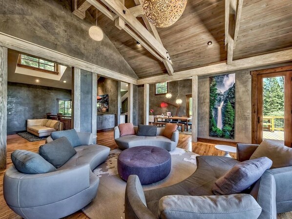 A spacious living area with modern furniture, large windows, and a high ceiling. - Lake View 545 Lodgepole | 6BR/6.5BA Incline | Hot Tub, Game Room (Incline Village)