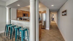 Une cuisine moderne avec des meubles en bois, des appareils en acier inoxydable et des tabourets de bar de couleur turquoise.