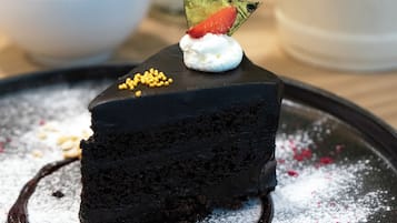 A slice of chocolate cake with white cream and a strawberry on a plate.
