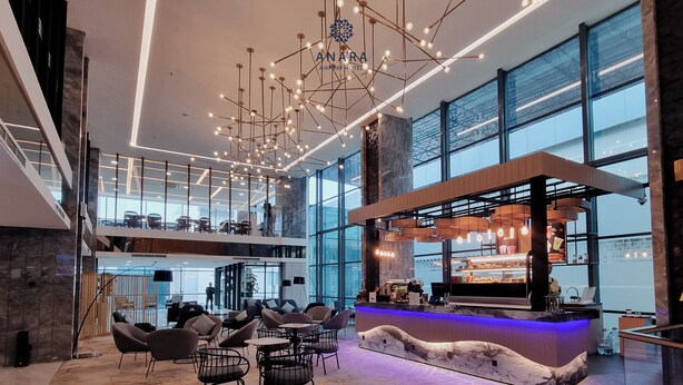 A modern hotel lobby with a central bar, seating area, and large windows. - Anara Airport Hotel (Tangerang)