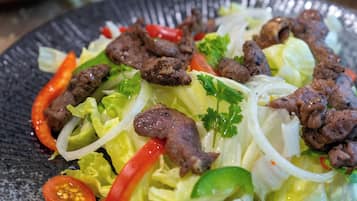 Een bord eten met vlees, sla en rode paprika.