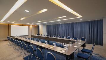 A conference room with a long table, chairs, and a projector screen.
