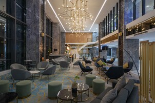 A modern lobby with a marble floor, seating areas, and a staircase.