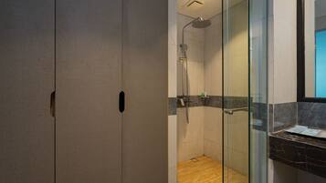 Un baño moderno con cabina de ducha de vidrio, suelo de madera y encimera de mármol.