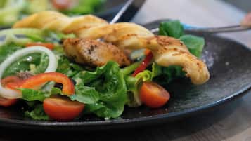 Une assiette de nourriture comprenant du poulet grillé, de la laitue, des tomates et des oignons.