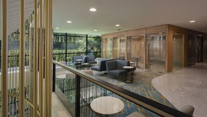 A modern interior with a glass railing, seating area, and a view of greenery outside. - Anara Airport Hotel (Tangerang)