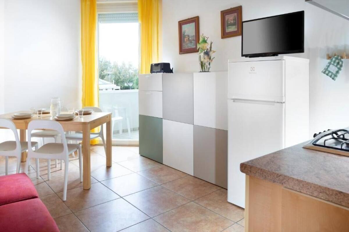 A compact kitchen with a dining area, a refrigerator, a stove, and a TV mounted above the counter.