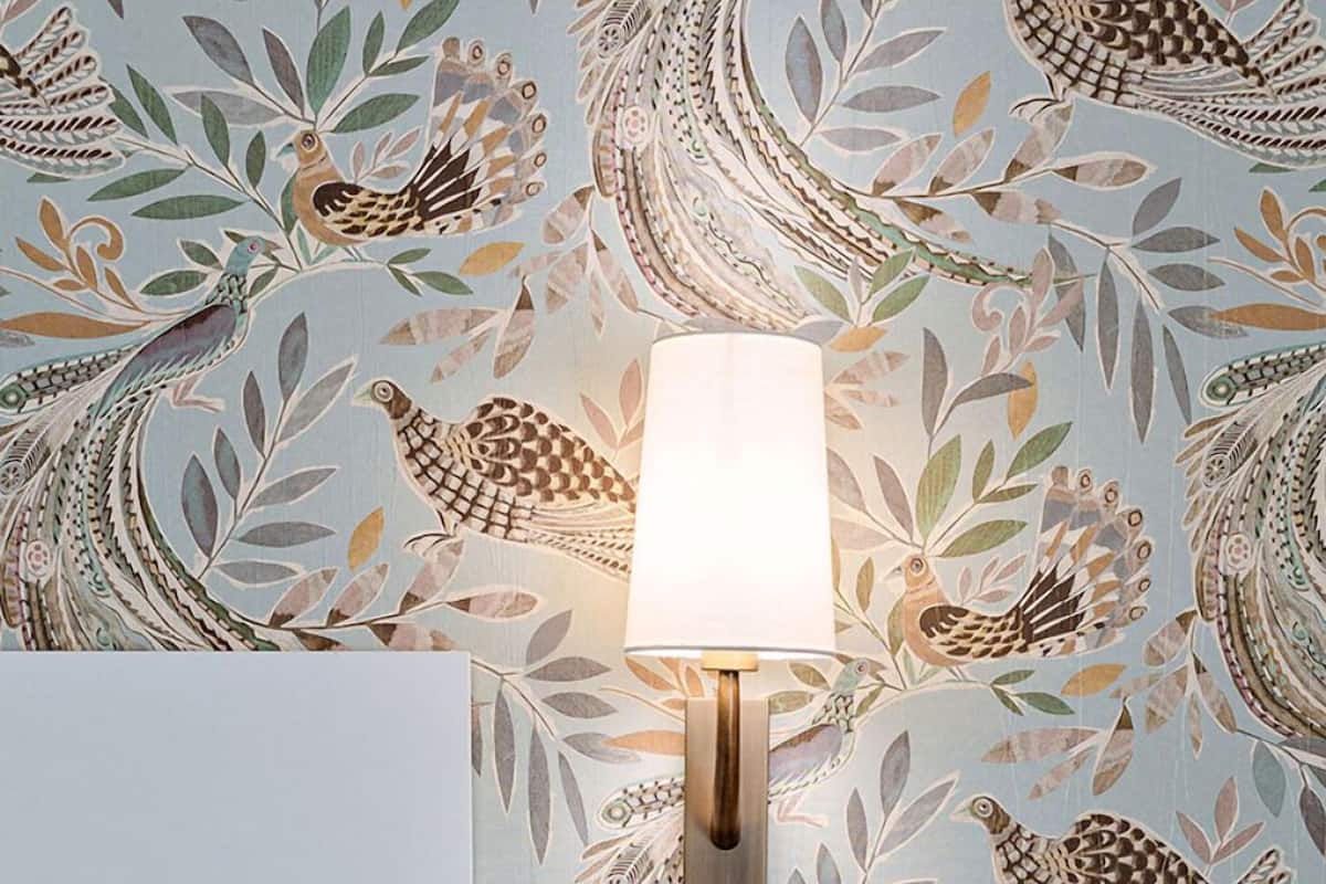 A wall with a decorative wallpaper featuring birds and leaves.