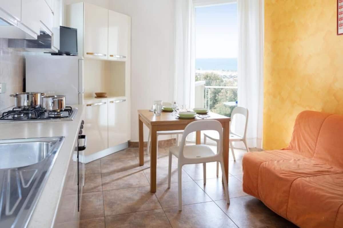 A compact kitchen with a stove, cabinets, and a dining area with a table and chairs.