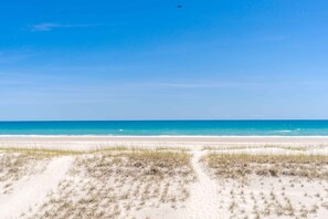 Una playa con dunas de arena y un cielo azul despejado.