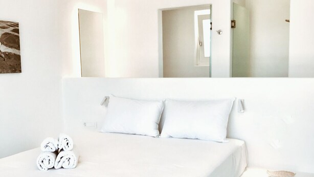 Een moderne hotelkamer met een groot bed, een nachtkastje en een spiegel.