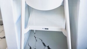 Een witte wastafel met spiegel, plank en een stopcontact.