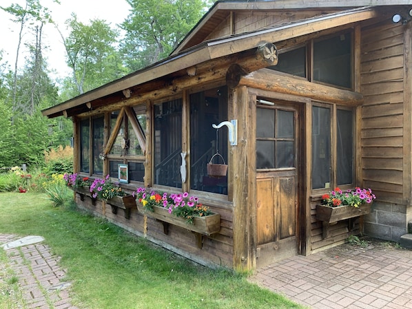 Un edificio rústico de madera con amplios ventanales y jardineras con flores a lo largo de la fachada.