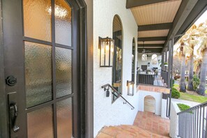 A staircase leading to a covered outdoor area with a railing, a door with frosted glass panels, and a wall-mounted light fixture.