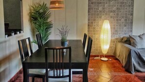 A dining area with a black table, six chairs, a hanging lamp, and a patterned wall. - Casa Rural La Goleta.  Pantano de San Juan (San Martín de Valdeiglesias)