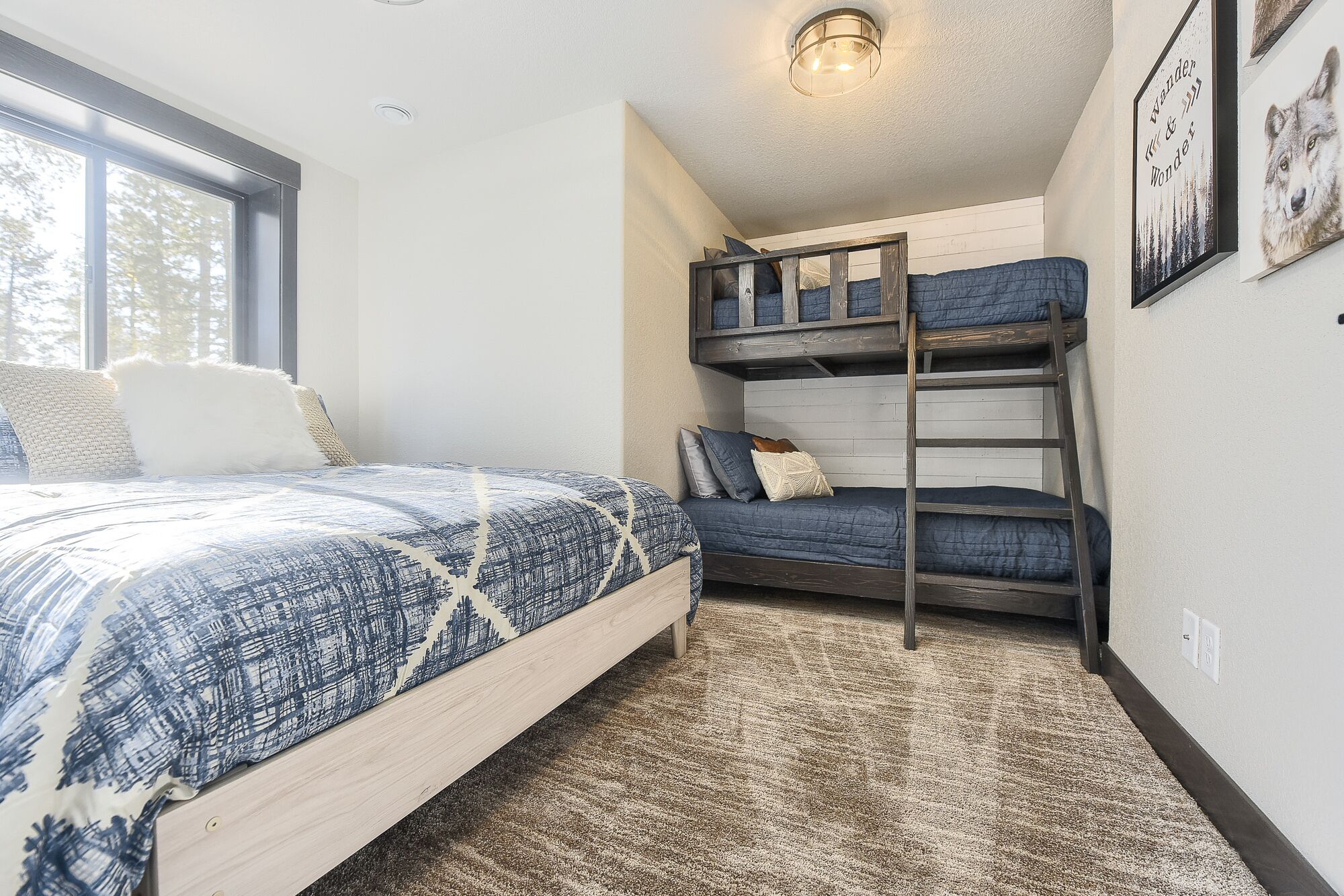 A bedroom with a bunk bed, a single bed, and a large window.