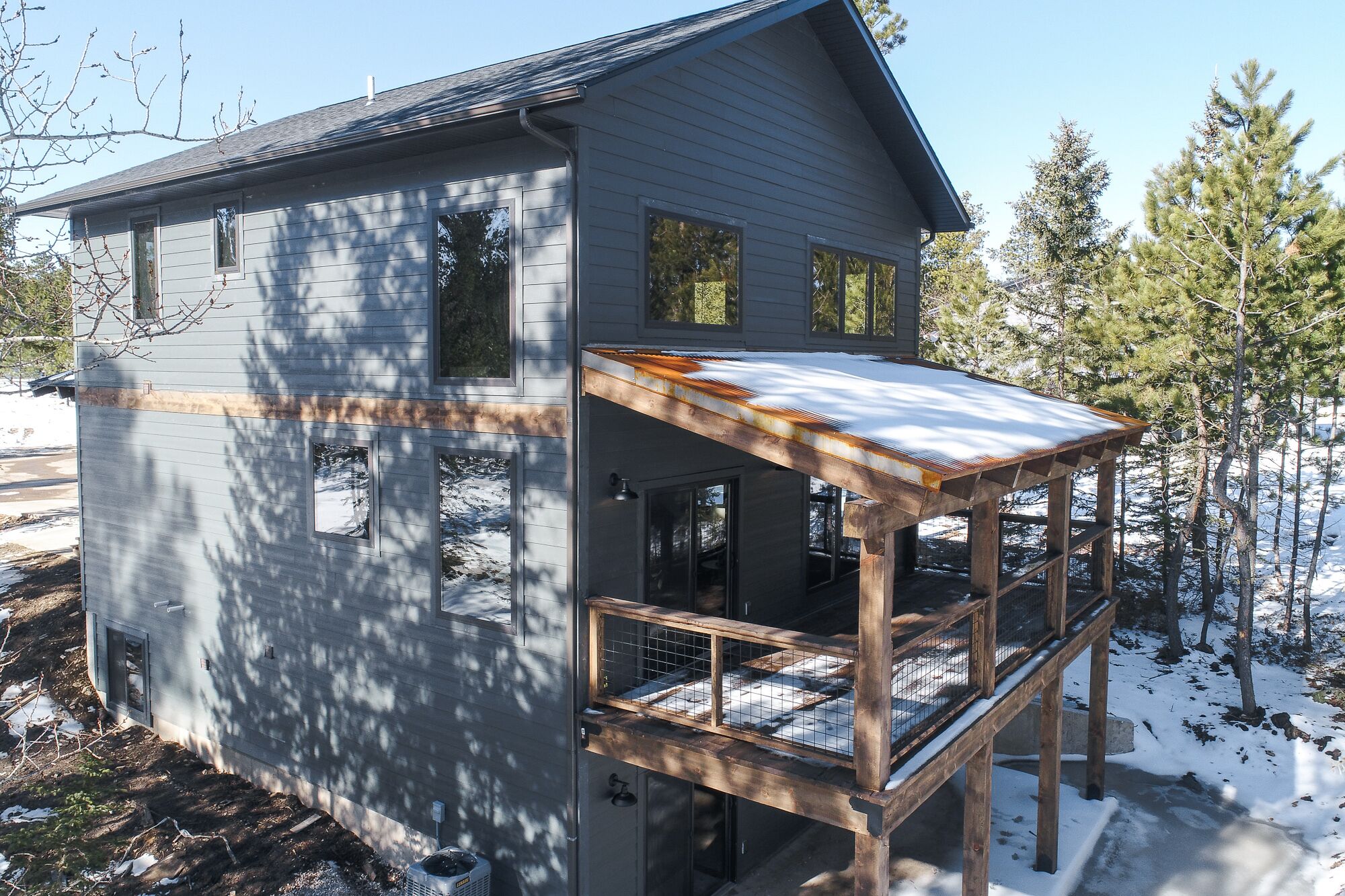 A two-story house with a wooden deck and a metal roof.